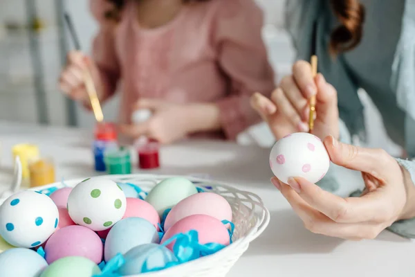 Fuoco selettivo di uova di Pasqua dipinte vicino a madre e figlia — Foto stock