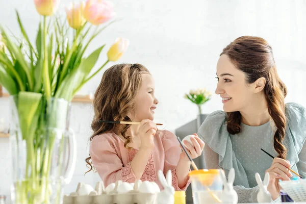 Happy mother and daughter looking at each other near easter eggs — Stock Photo