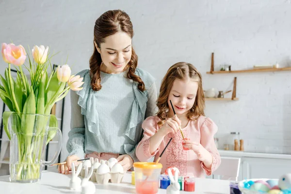 Selective focus of child and mother near tulips and easter eggs — Stock Photo