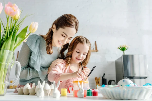 Fuoco selettivo di bambino felice e madre vicino a tulipani e uova di Pasqua — Foto stock