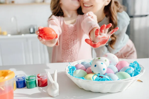Selective focus of painted easter eggs near decorative rabbit, mother and daughter — Stock Photo
