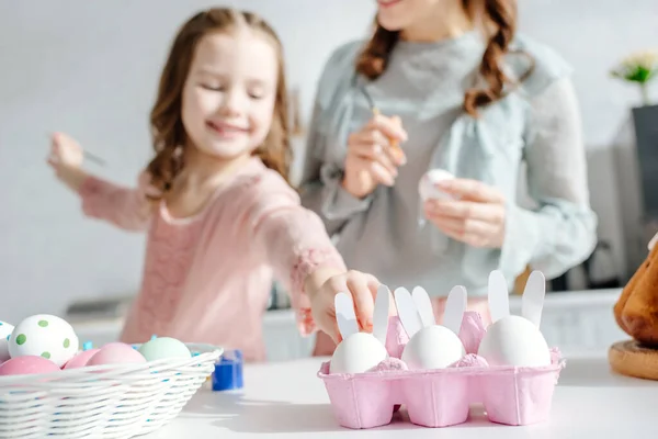 Enfoque selectivo de lindo niño tomando huevo de gallina cerca de la madre - foto de stock