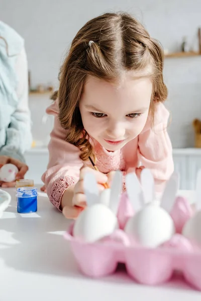 Selective focus of cute kid near chicken eggs and mother — Stock Photo