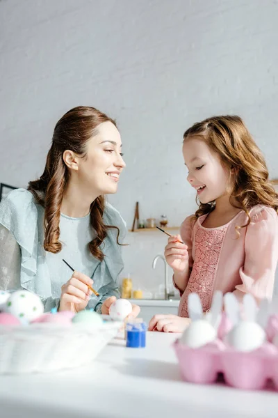 Selective focus of cheerful mother and daughter near painted easter eggs — Stock Photo