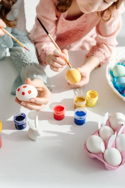 Vista ritagliata di madre e bambino pittura uova di Pasqua vicino coniglio decorativo — Foto stock