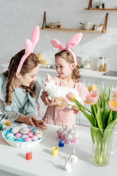 Mãe perto de filha bonito em orelhas de coelho com coelho de brinquedo — Fotografia de Stock