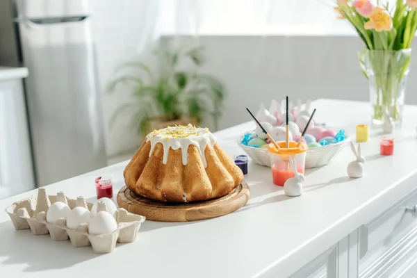 Gâteau de Pâques doux près des œufs de poulet peints, des tulipes et des lapins décoratifs — Photo de stock