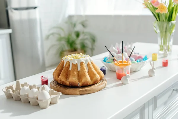 Süßer Osterkuchen neben bemalten Hühnereiern, Tulpen und Zierhasen — Stockfoto