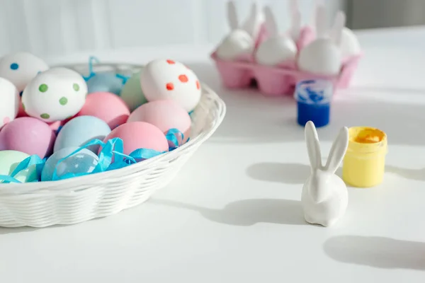 Ovos de Páscoa pintados perto de coelho decorativo e jarros com pintura — Fotografia de Stock