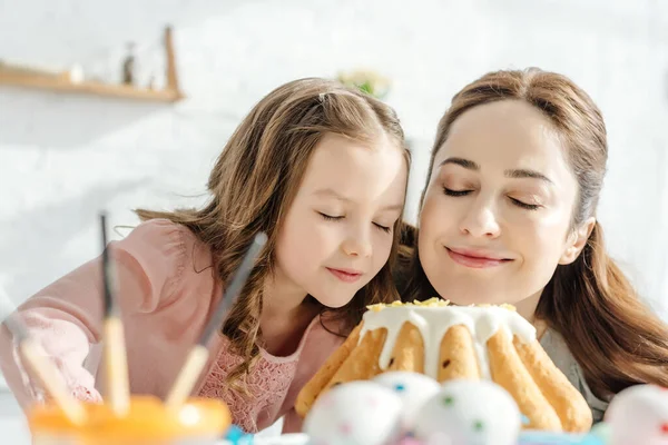 Selective focus of happy mother and daughter smelling easter cake — Stock Photo