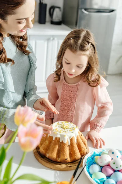 Селективный фокус матери и дочери рядом с эфирным хлебом и тюльпанами — стоковое фото