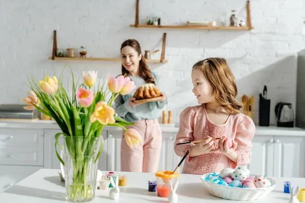 Selective focus of kid near chicken eggs and mother with easter cake — Stock Photo