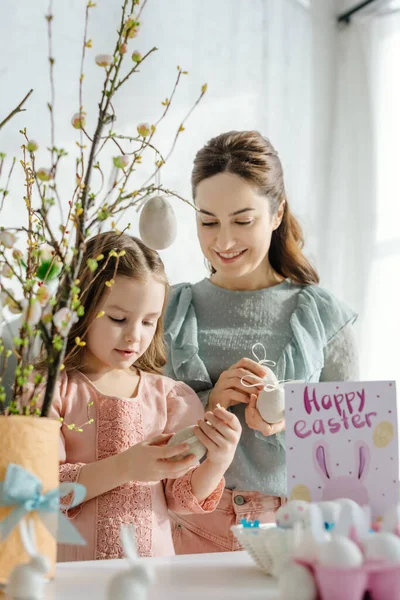 Selective focus of happy mother and kid near willow and easter eggs — Stock Photo