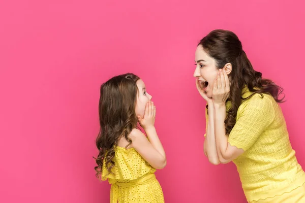 Excited mother and daughter looking at each other isolated on pink — Stock Photo
