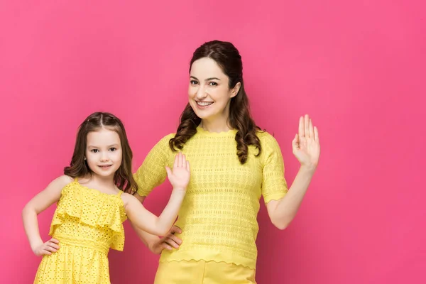 Happy mother and daughter waving hands isolated on pink — Stock Photo