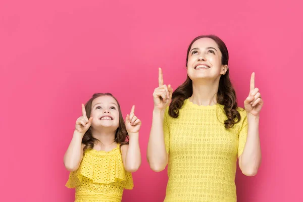Счастливая женщина и ребенок, показывающие пальцами на розовом — стоковое фото
