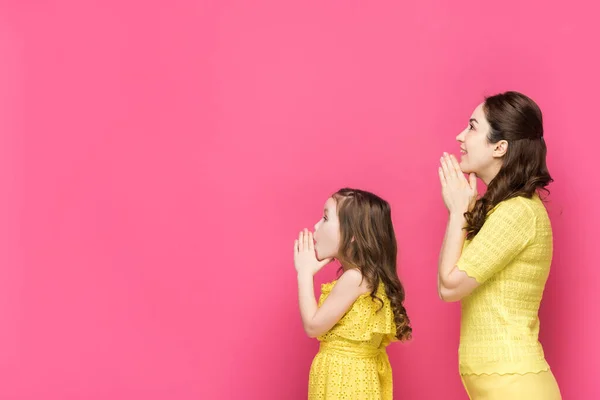 Profil de la mère et de la fille avec les mains priantes isolées sur rose — Photo de stock