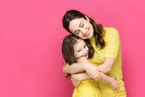 Cheerful mother and daughter hugging isolated on pink — Stock Photo