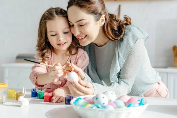 Selective focus of happy mother and daughter painting chicken egg — Stock Photo