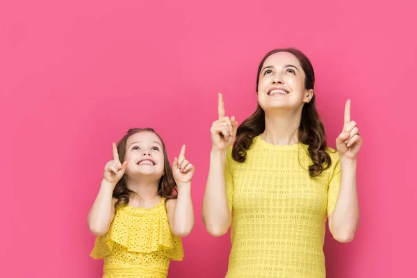 Felice madre e bambino puntando con le dita e guardando in alto isolato su rosa — Foto stock