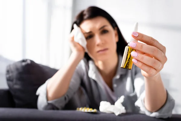 Selective focus of upset woman with allergy looking at nasal spray — Stock Photo