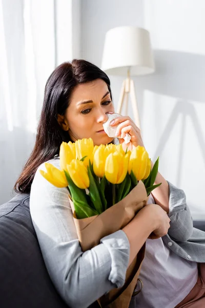 Sad woman with pollen allergy looking at tulips — Stock Photo