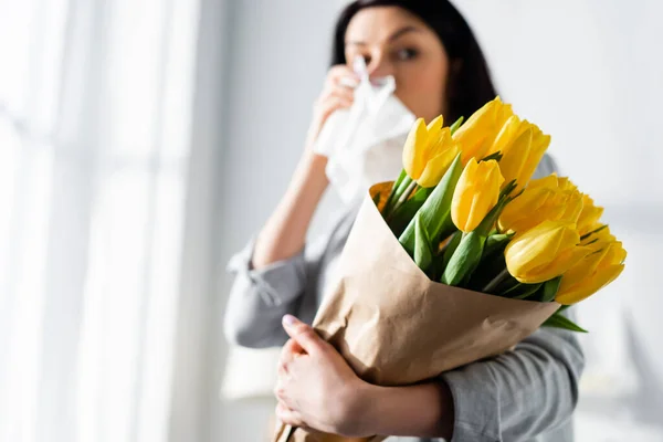 Foco seletivo da mulher com alergia ao pólen e corrimento nasal segurando tulipas — Fotografia de Stock