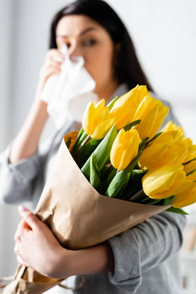 Selective focus of tulips in hand of woman with pollen allergy and running nose — Stock Photo