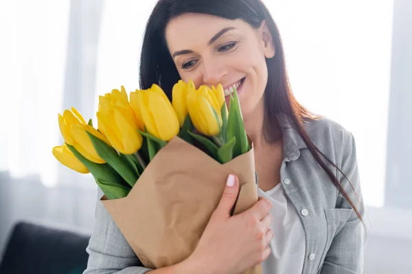 Mulher feliz sorrindo e olhando para tulipas — Fotografia de Stock