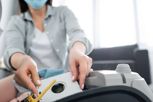 Vista recortada de la mujer alérgica en la máscara médica que sostiene la bolsa de polvo cerca de la aspiradora - foto de stock