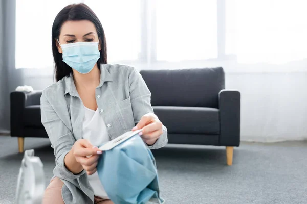 Enfoque selectivo de la mujer alérgica en la máscara médica que sostiene la bolsa de polvo - foto de stock