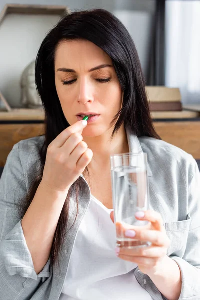 Mujer alérgica tomando píldora y sosteniendo un vaso de agua - foto de stock
