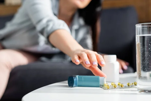 Vue recadrée de la femme atteignant pour inhalateur sur la table basse — Photo de stock