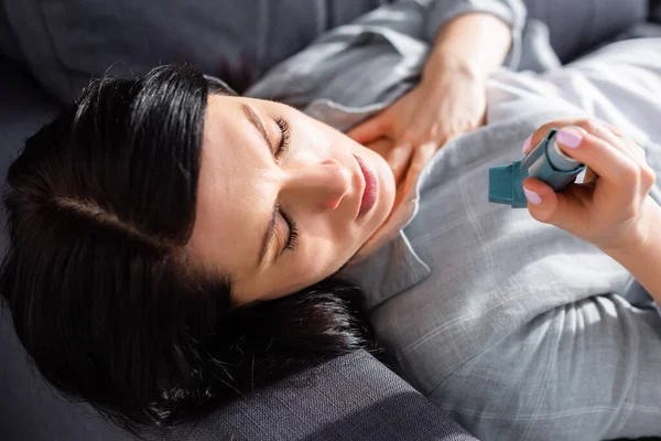 Overhead view of woman with asthma looking at inhaler at home — Stock Photo