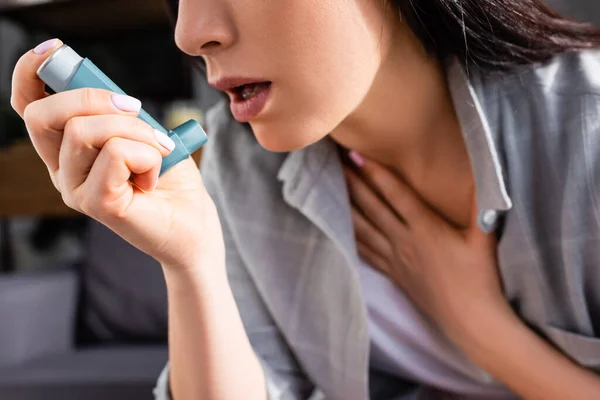 Cropped view of sick woman holding inhaler at home — Stock Photo