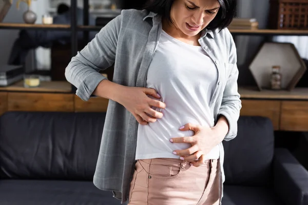 Mulher chateada com alergia coçar o estômago em casa — Fotografia de Stock