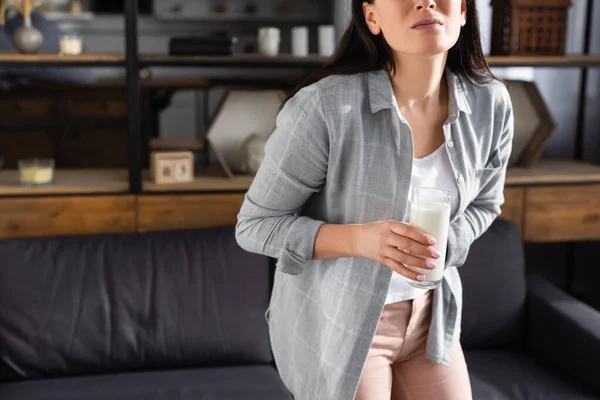 Обрезанный вид женщины с непереносимостью лактозы, держащей стакан молока — стоковое фото