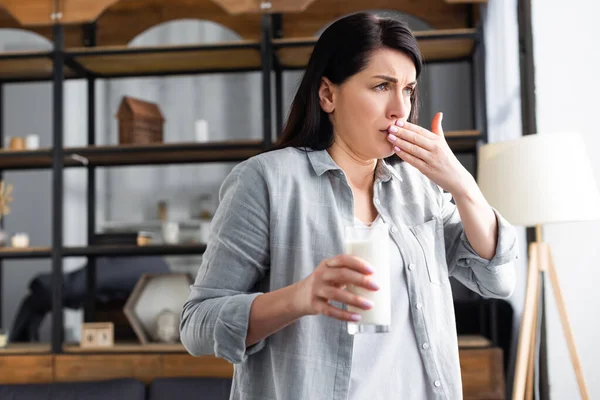 Donna intollerante al lattosio che tiene un bicchiere di latte e copre la bocca — Foto stock