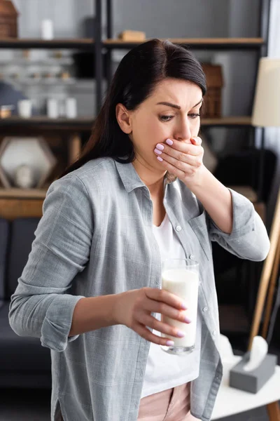 Mulher com intolerância à lactose e náuseas olhando para o copo de leite — Fotografia de Stock