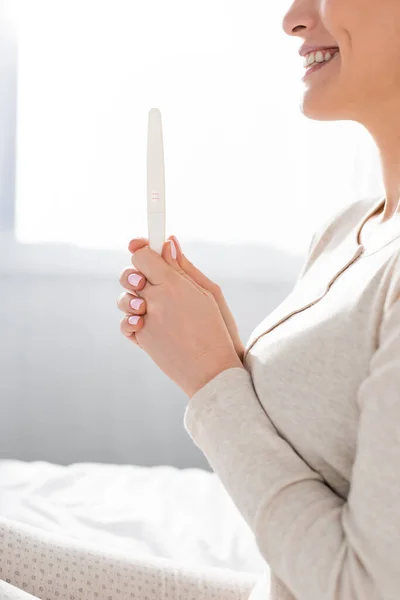 Vista recortada de la mujer sonriente sosteniendo la prueba de embarazo - foto de stock