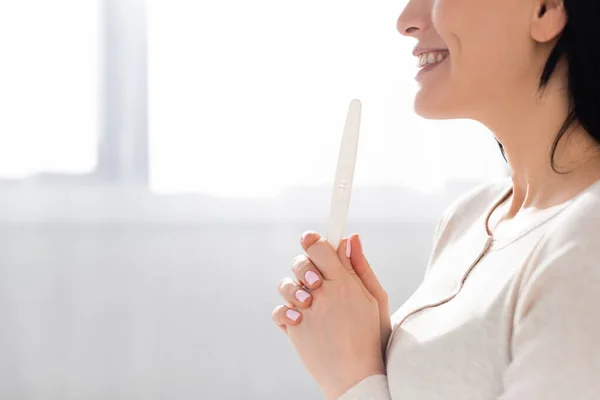 Vista cortada de mulher alegre segurando teste de gravidez — Fotografia de Stock