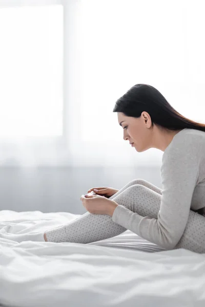 Vue latérale de la femme déprimée tenant un test de grossesse avec un résultat négatif — Photo de stock