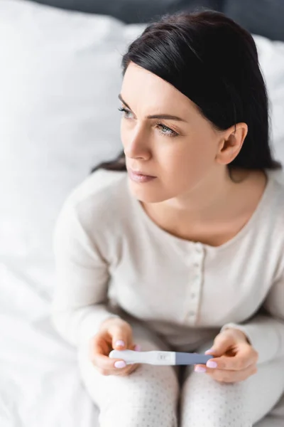 Селективный фокус грустной женщины, проводящей тест на беременность с отрицательным результатом — стоковое фото