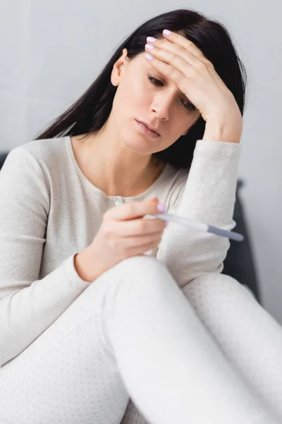 Selective focus of displeased woman holding pregnancy test with negative result — Stock Photo