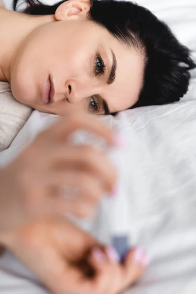 Selective focus of woman lying on bed and looking at pregnancy test with negative result — Stock Photo