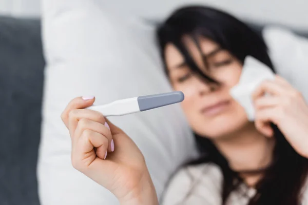 Selektiver Fokus trauriger Frau beim Blick auf Schwangerschaftstest mit negativem Ergebnis im Bett — Stockfoto