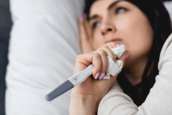 Selective focus of sad woman holding pregnancy test with negative result and tissue — Stock Photo