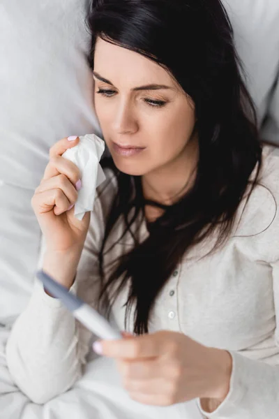 Selective focus of sad woman holding napkin and pregnancy test with negative result — Stock Photo