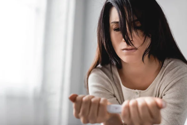 Foyer sélectif de la femme déçue tenant un test de grossesse avec un résultat négatif — Photo de stock