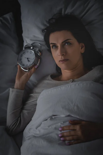 Top view of awake woman lying on bed with alarm clock — Stock Photo